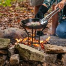 Lodge stojan na varenie s liatinovým riadom v otvorenom ohni